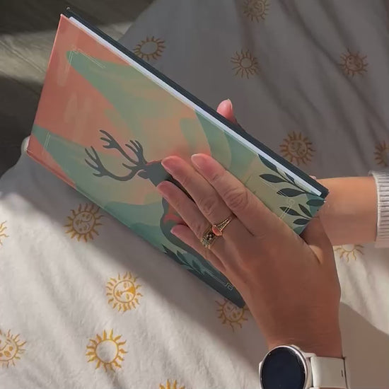 Démonstration de l’Astrobook Plumastro : une jeune femme feuillette un livre d’astrologie personnalisé avec thème astral, planètes et animal totem sur la couverture.